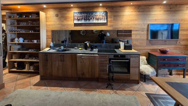 A modern kitchen with wooden cabinetry, a central island, and a built-in oven. - Le Menhir, Chalets de Lady (Megève)