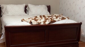 A wooden bed with white bedding and a brown and white blanket.