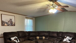 A sectional sofa with a recliner, a ceiling fan, and a wooden floor.
