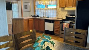 A compact kitchen with wooden cabinets, a built-in stove, and a dining table with chairs.