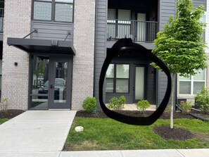 A modern two-story building with a brick facade, a glass entrance, and a small tree in the front yard. - Ore 1bed/1bth - King Bed (Noblesville)