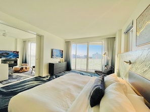 Una habitación de hotel con cama, televisión, escritorio y vistas a la ciudad.