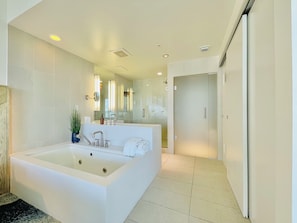 Un baño moderno con una bañera grande, un espejo y un lavamanos.
