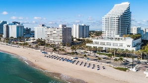 Ein Strandhotel mit mehreren Hochhäusern, einem Sandstrand und blauem Himmel.