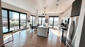 Een moderne keuken met een centraal eiland, grote ramen en uitzicht op de stad.