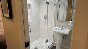 Ein modernes Badezimmer mit einer gläsernen Duschkabine, einem Standwaschbecken und einem großen Spiegel.