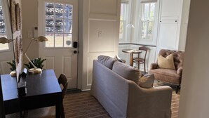 Ein gemütliches Wohnzimmer mit einem dunklen Holztisch, einem grauen Sofa und einem braunen Ledersessel.