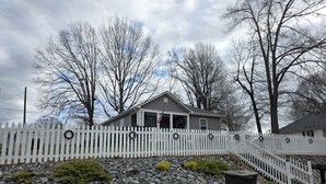 A house with a white picket fence, stone retaining wall, and a front porch.
