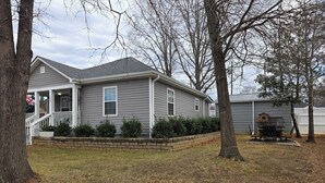 A residential house with a porch, a small deck, and a well-maintained lawn.