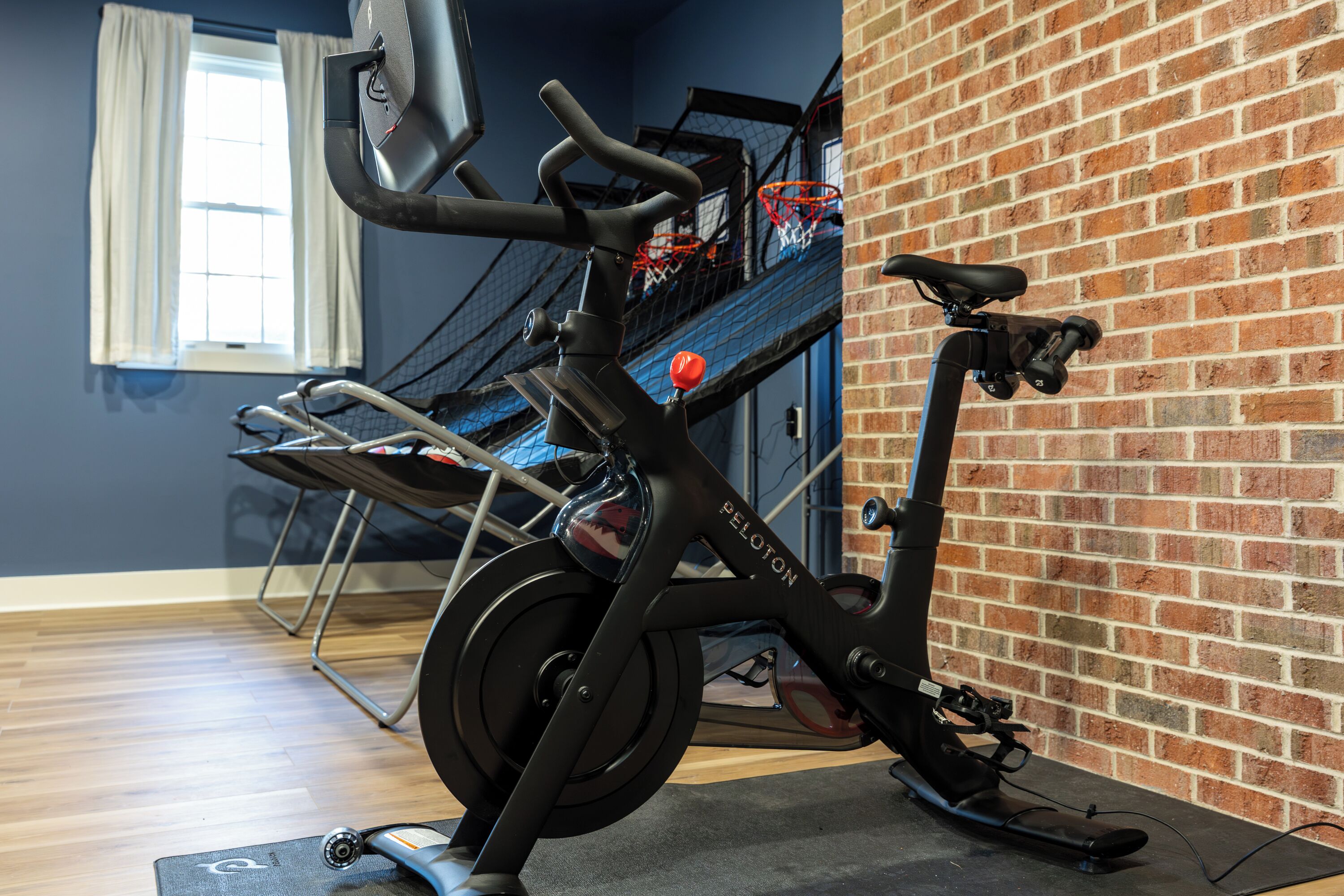 A stationary bike in a room with a brick wall and a window with curtains.