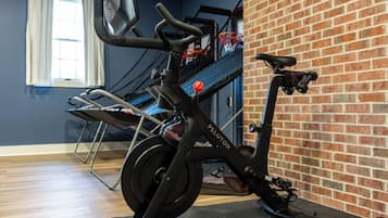 A stationary bike in a room with a brick wall and a window with curtains.