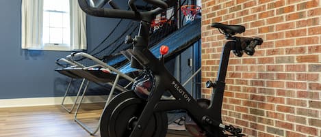 Una bicicleta estática en una habitación con pared de ladrillo y ventana con cortinas.