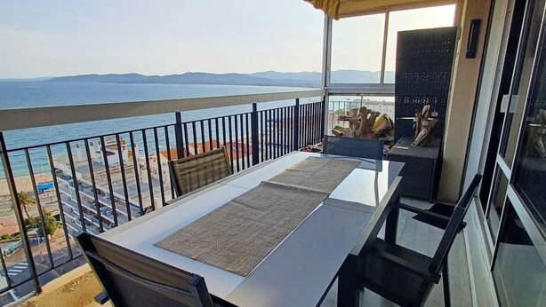 A balcony with a table and chairs, overlooking a coastal view. - Sea view apartment (Saint-Raphaël)