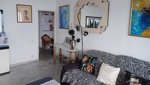 A living room with a zebra-patterned sofa, a decorative mirror, and various artworks on the walls. - Sea view apartment (Saint-Raphaël)