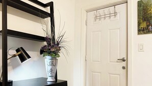 A room with a white door, a black shelf with a desk lamp, a white vase with a plant, and a wooden chair. - UInn-At UPenn; 1C- with a private courtyard and separate entrance. (Philadelphia)