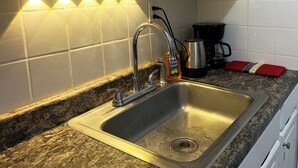 A kitchen with a stainless steel sink, a coffee maker, and a hand soap dispenser. - UInn-At UPenn; 1C- with a private courtyard and separate entrance. (Philadelphia)