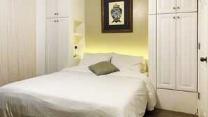 A bedroom with a bed, white wardrobe, and a framed picture on the wall. - UInn-At UPenn; 1C- with a private courtyard and separate entrance. (Philadelphia)