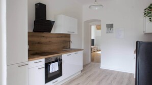 A modern kitchen with white cabinets, a wooden countertop, a black range hood, and a black refrigerator. - Bright apartment in the city center (Graz)