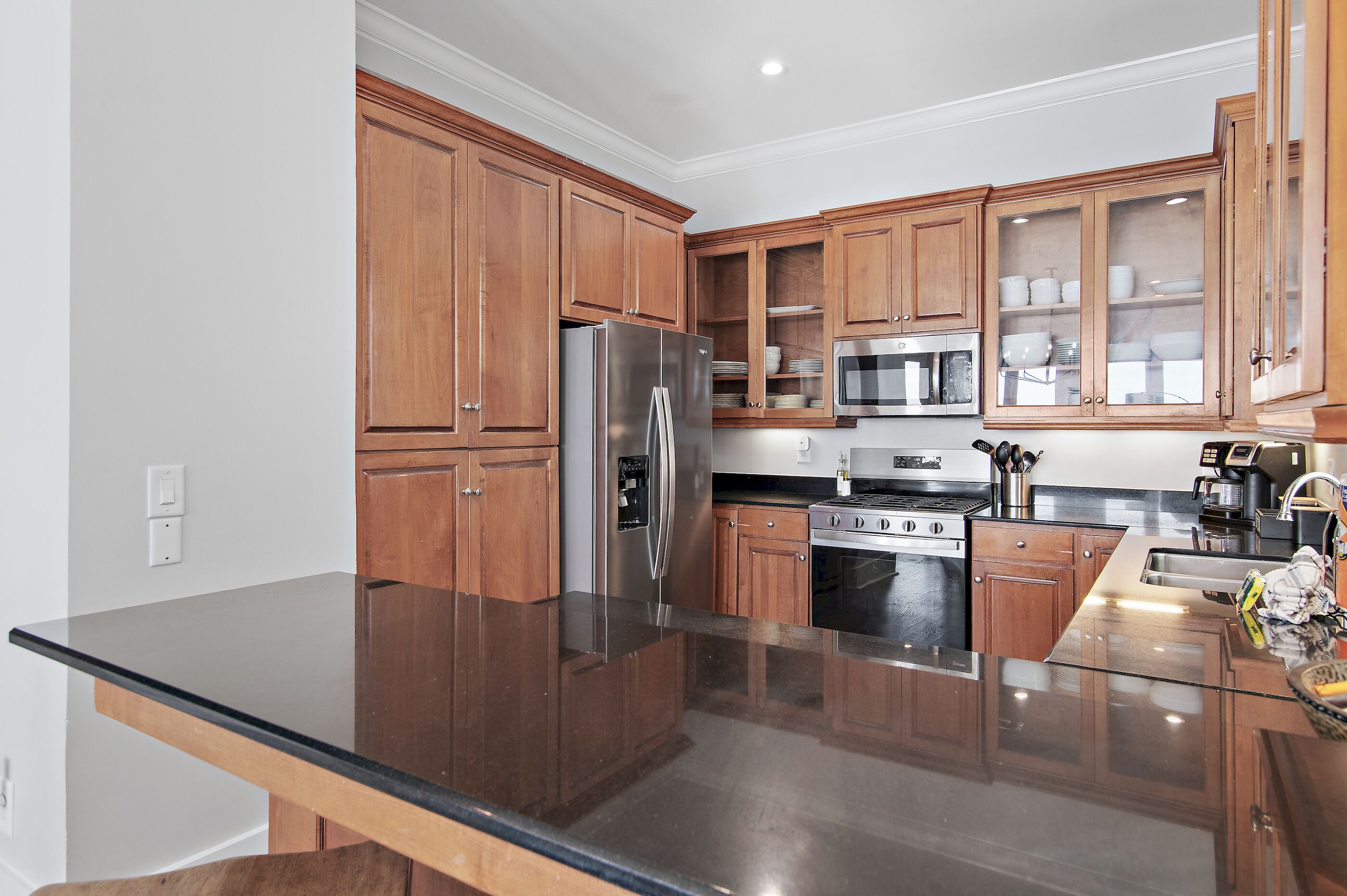 A modern kitchen with wooden cabinets, stainless steel appliances, and a black countertop.