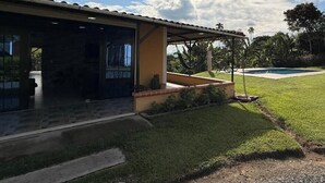 A house with a covered patio, a swimming pool, and a well-maintained lawn. - PARCEROS GROUP - LARGE FARM HOUSE FOR GROUPS IN PEREIRA (La Estrella)