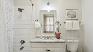 Een badkamer met douche, toilet, wastafel en spiegel.