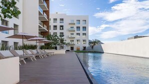 Un hôtel moderne doté d’une piscine sur le toit, de chaises longues et de parasols.