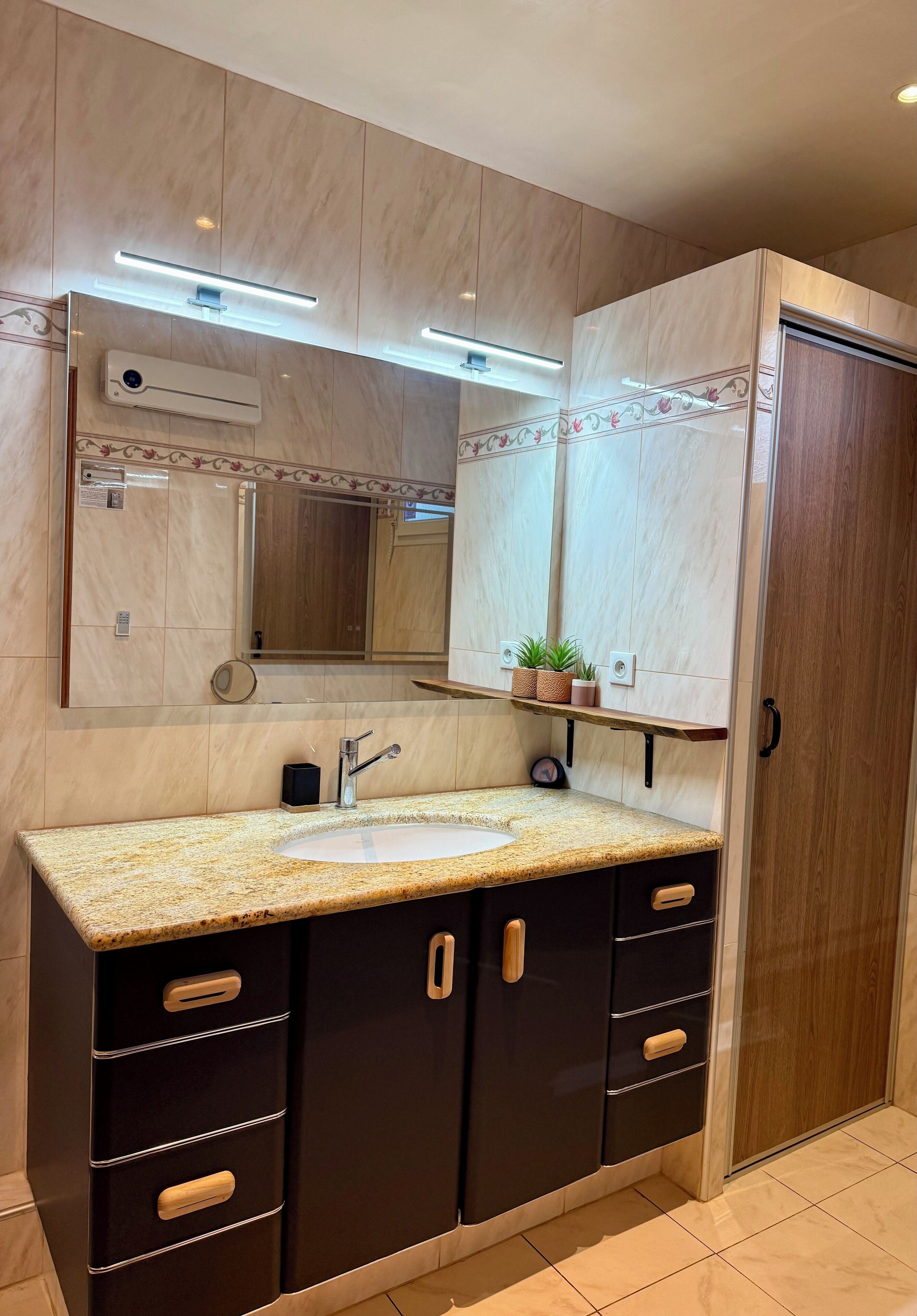 A bathroom with a marble vanity, a sink, a mirror, and a cabinet with drawers.