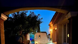 Un vialetto lastricato conduce a un edificio con facciata in pietra, piante in vaso e illuminazione esterna.