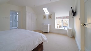 A bedroom with a large bed, a wardrobe, a dresser, a radiator, and a window with a view. - Charming Barn Conversion, Idyllic Somerset Village (Somerset)