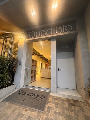 The entrance to a building with a sign reading "Quadrato Studios." - Cozy 1-bedroom studio in peaceful Medellin with AC and gym (Medellin)