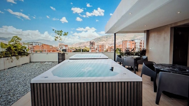 Eine Dachterrasse mit Whirlpool, Sitzgelegenheit und Blick auf die Stadtlandschaft.