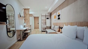 Ein modernes Hotelzimmer mit einem großen Bett, einem Schreibtisch, einem Sessel und einem Spiegel.