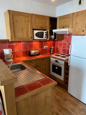 A compact kitchen with wooden cabinets, a microwave, a toaster, a kettle, and a refrigerator. - Le Corbier, at the foot of the slopes. Apartment 6 pers, 44m². Galaxie building (Villarembert)