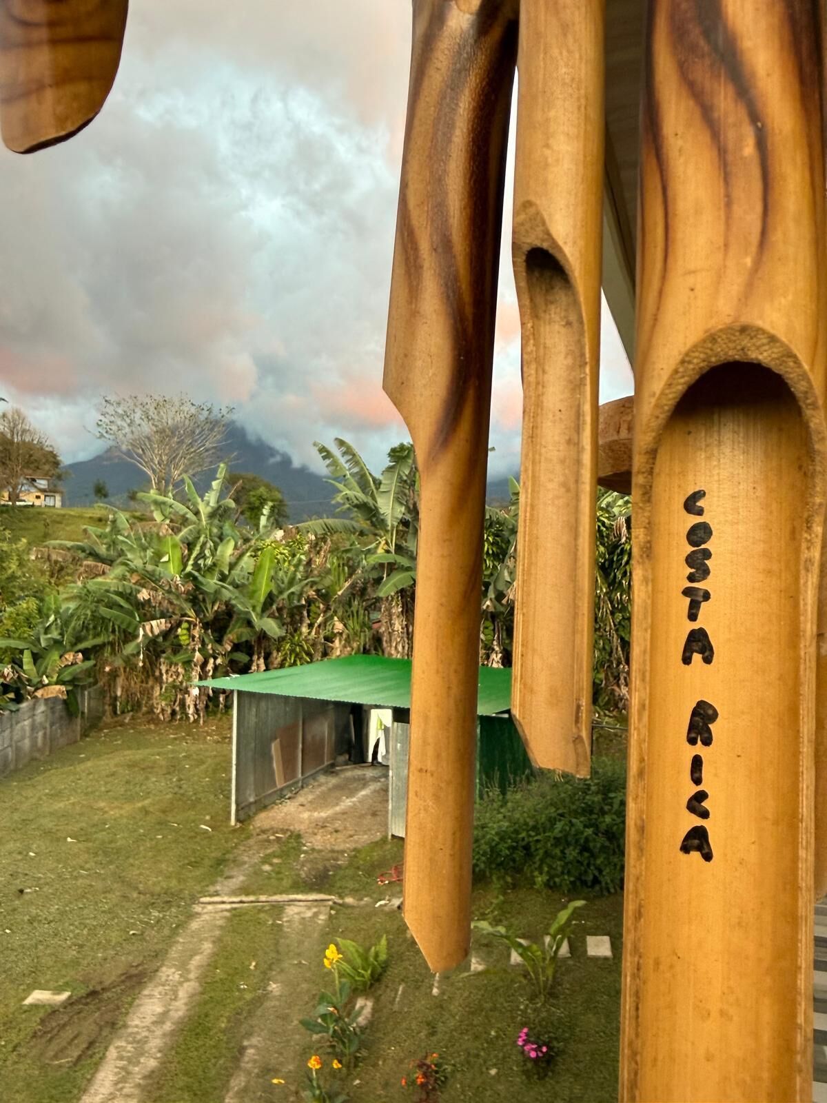 En träkonstruktion med texten ”Costa Rica” på, omgiven av grönska och en molnig himmel.