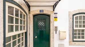Un edificio con una puerta verde, un cartel con el número 13 encima y un teclado de seguridad en la pared.