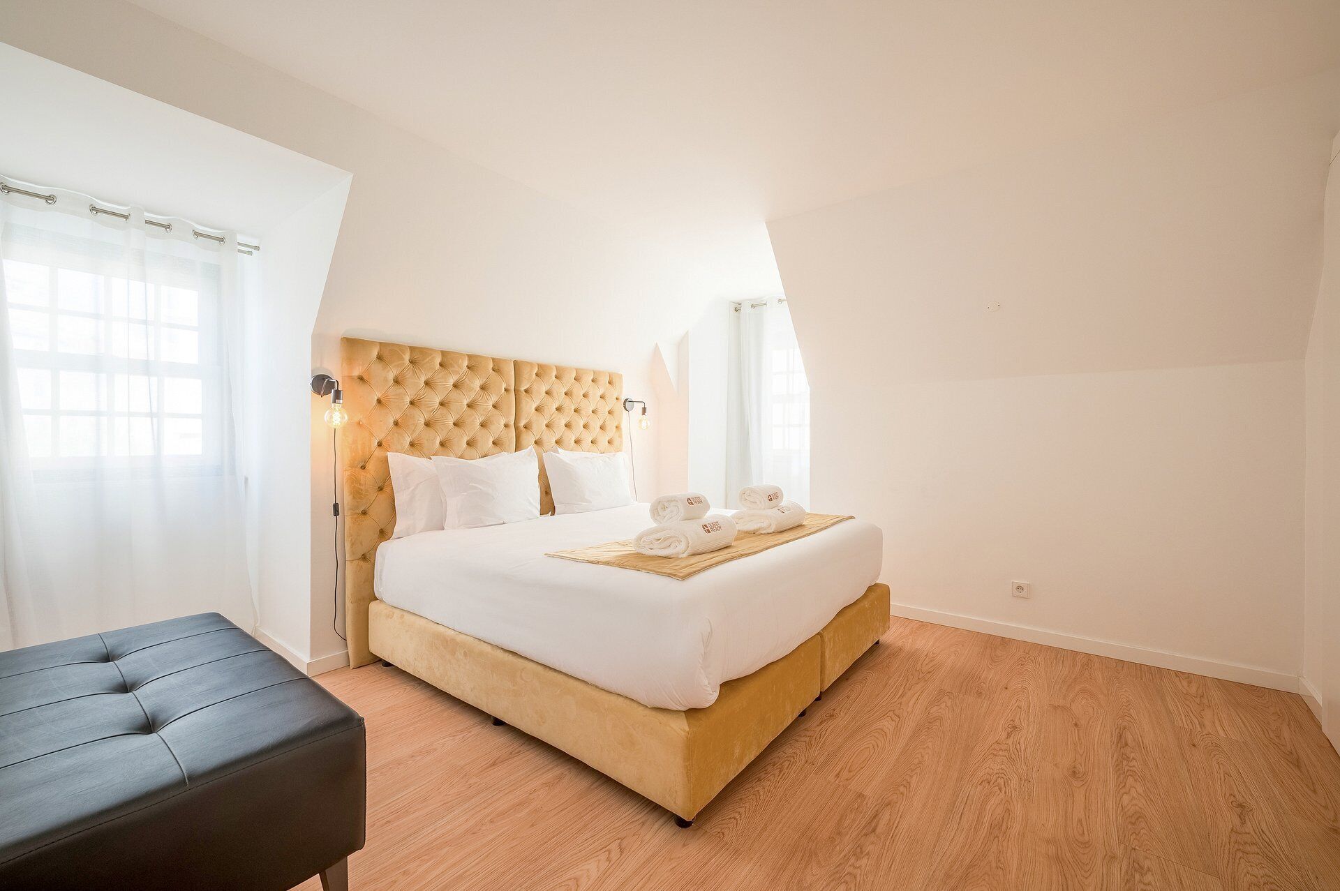 A bedroom with a bed, a bedside table, a lamp, and a window with curtains.