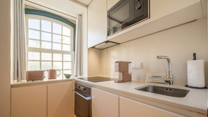 A modern kitchen with a microwave, coffee maker, and a cleaning kit on the counter. - Guestready - The Corner 2E (Lisbon)