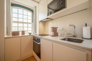 Eine moderne Küche mit Mikrowelle, Kaffeemaschine und Reinigungsmittel auf der Arbeitsfläche.