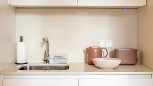 A kitchen with a sink, a faucet, a cleaning kit, a kettle, a mug, and a bowl. - Guestready - The Corner 2D (Lisbon)