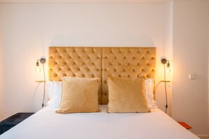 A hotel room with a tufted headboard, two bedside lamps, and two pillows. - Guestready - The Corner 2D (Lisbon)