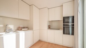 A compact kitchen with white cabinetry, a stainless steel oven, and a wooden floor. - Guestready - The Corner 2D (Lisbon)