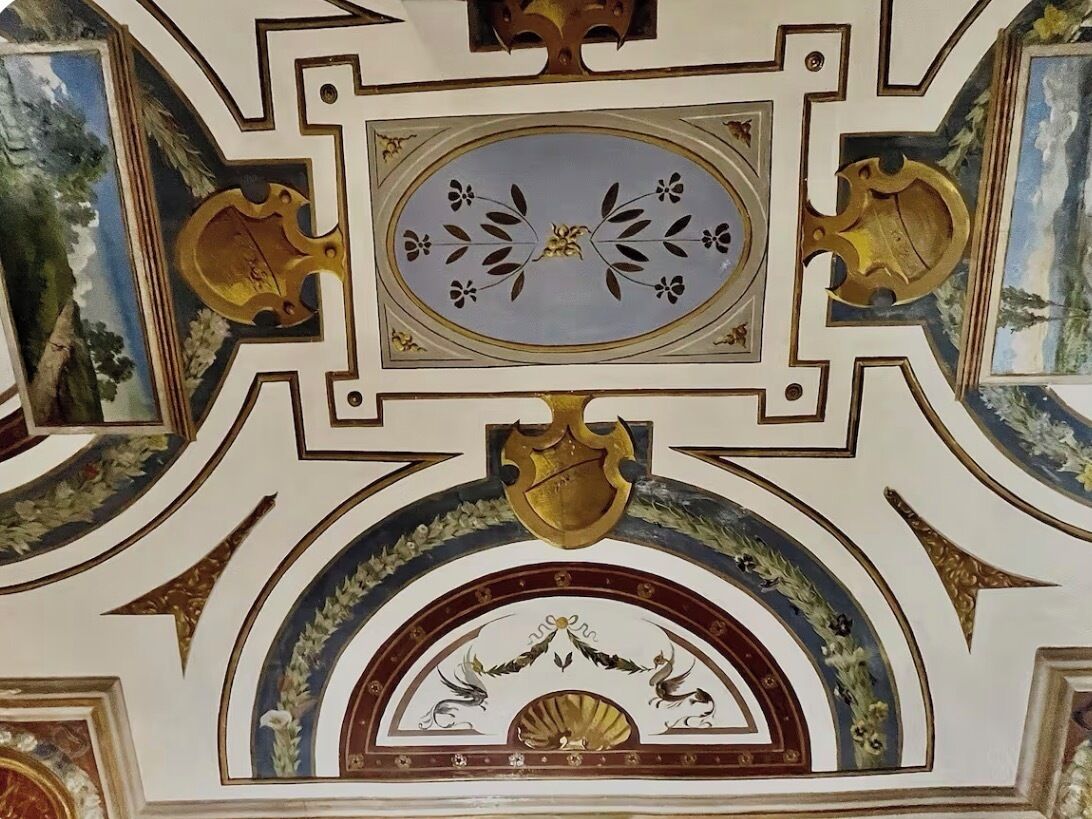A detailed ceiling with ornate gold accents and a central oval design.