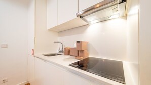 Une cuisine moderne avec des meubles blancs, un évier en acier inoxydable, un four encastré et une hotte aspirante.