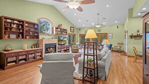 A spacious living room with a fireplace, wooden furniture, and a ceiling fan. - Fisherman's Cove -Waterfront home with private dock on the River sleeps 10 (Steinhatchee)