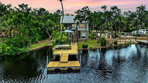 A house with a dock extending into a body of water, surrounded by lush greenery and palm trees. - Fisherman's Cove -Waterfront home with private dock on the River sleeps 10 (Steinhatchee)