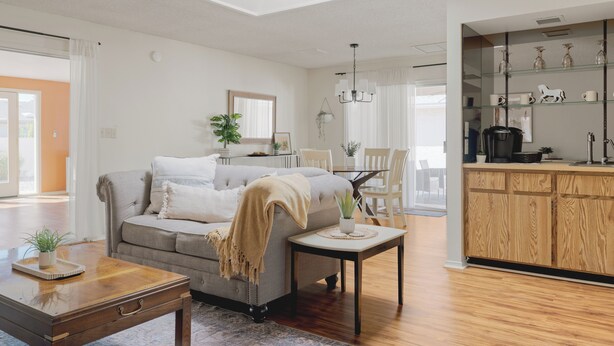 A modern living room with a sofa, coffee table, and a dining area with chairs.