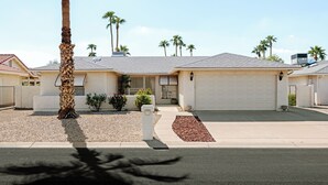 A residential house with a garage, a driveway, and a palm tree in the foreground.