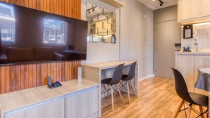A modern kitchen with wooden cabinetry, a built-in bar area, and a dining space with black chairs. - Moderno Est dio Frei Caneca a 1 km da Av Paulista (São Paulo)