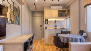 A compact kitchen with a central island, a dining area with a table and chairs, and a small seating area with a sofa. - Moderno Est dio Frei Caneca a 1 km da Av Paulista (São Paulo)