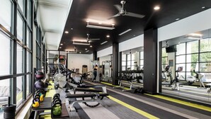 Una palestra con attrezzi per allenamento, ampie finestre e ventilatori a soffitto.